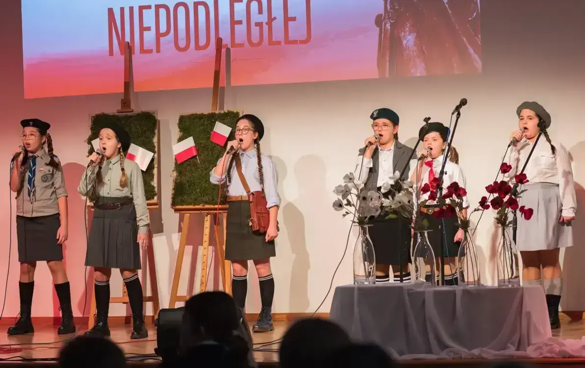 Zdjęcie predstawia zespół dziecięcy wykonujący pisenkę patriotyczną na konkursie