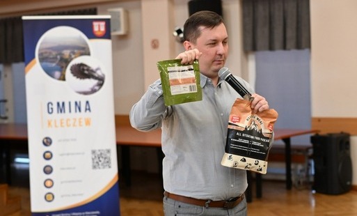 Zdjęc ie przedstawia prelegenta, który pokazuje słuchaczom pakiet posiłków kryzysowych